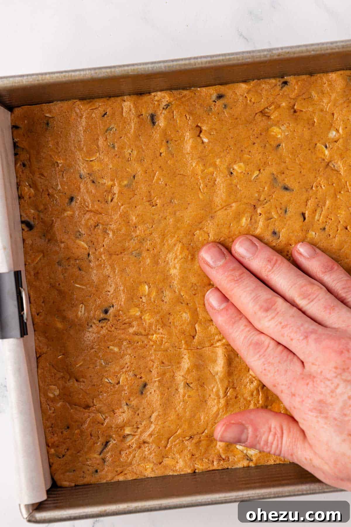 Close-up of hand pressing the protein bar batter smoothly