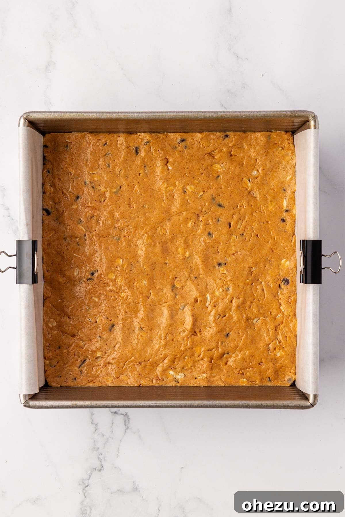 Protein bar batter uniformly pressed in a lined baking dish