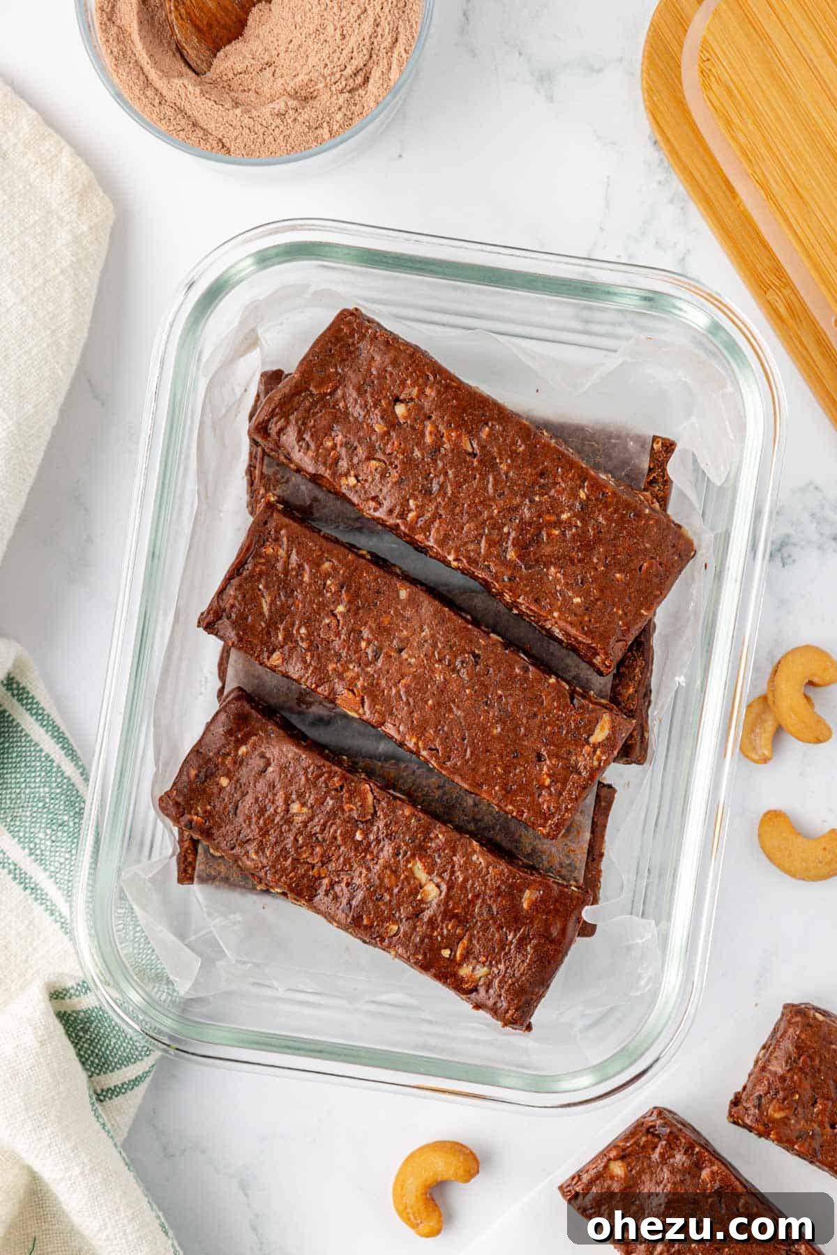 Chocolate cashew protein bars neatly packed in a storage container, separated by wax paper