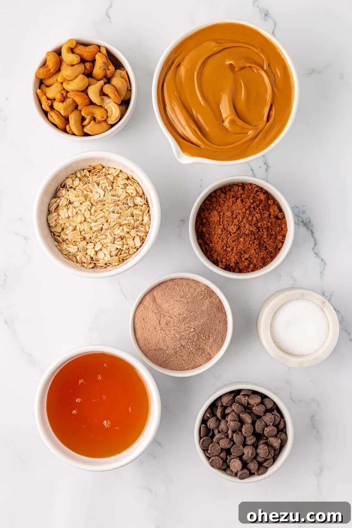 Arrangement of ingredients needed to make chocolate cashew protein bars on a light surface