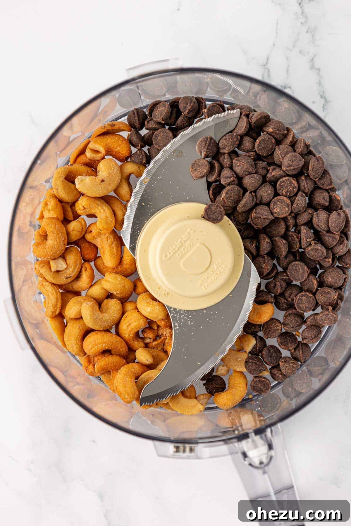 Dark chocolate chips and cashews placed in a food processor bowl