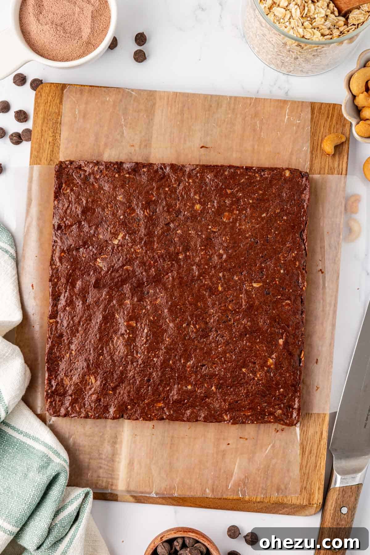 Chilled block of chocolate cashew protein bar mixture on a cutting board, ready for slicing