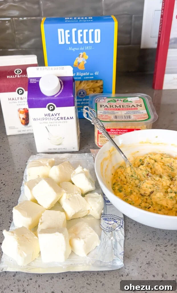 Creamy Garlic Parmesan Chicken Pasta 4 Ingredients for Garlic Parmesan Chicken Pasta displayed on a cutting board