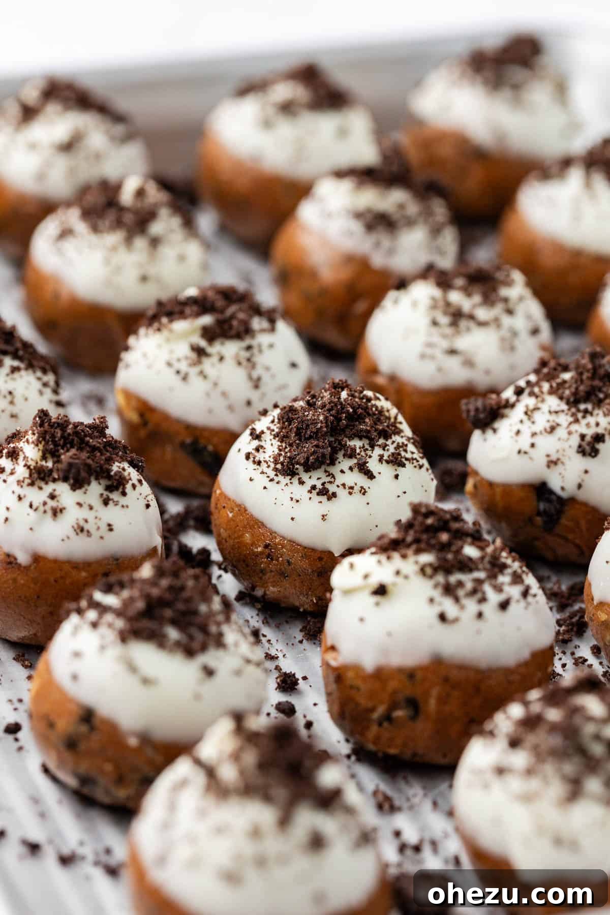 Close-up of protein ball batter being scooped onto a wax paper-lined baking sheet.