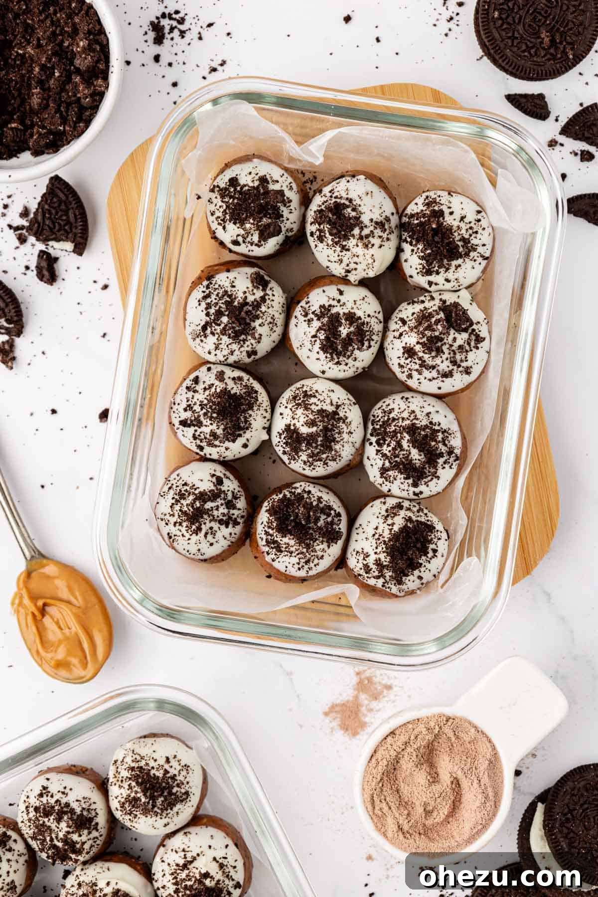 Finished cookies and cream protein balls on a baking sheet, with white chocolate drizzle and crushed Oreos.