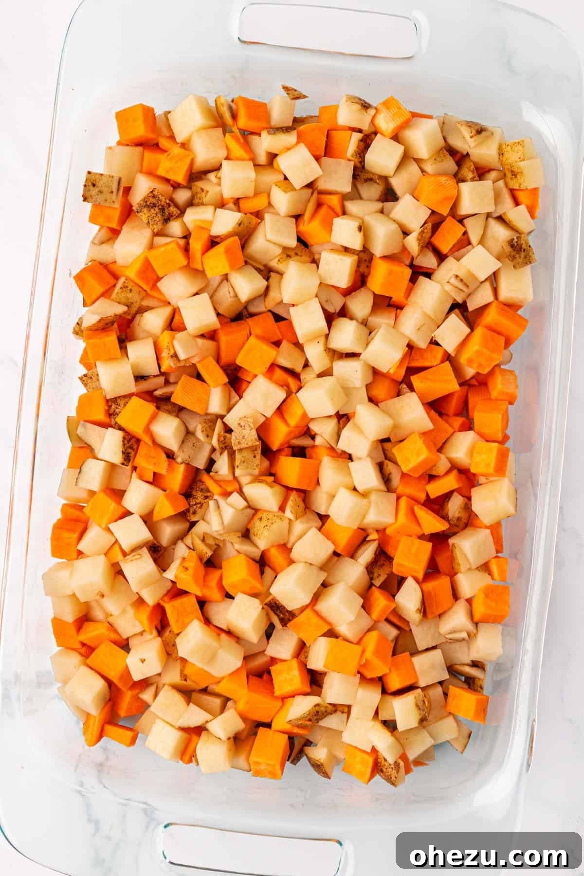 Plant-Powered Breakfast Hash 5 Diced russet and sweet potatoes coated with olive oil and spices in a large baking dish.