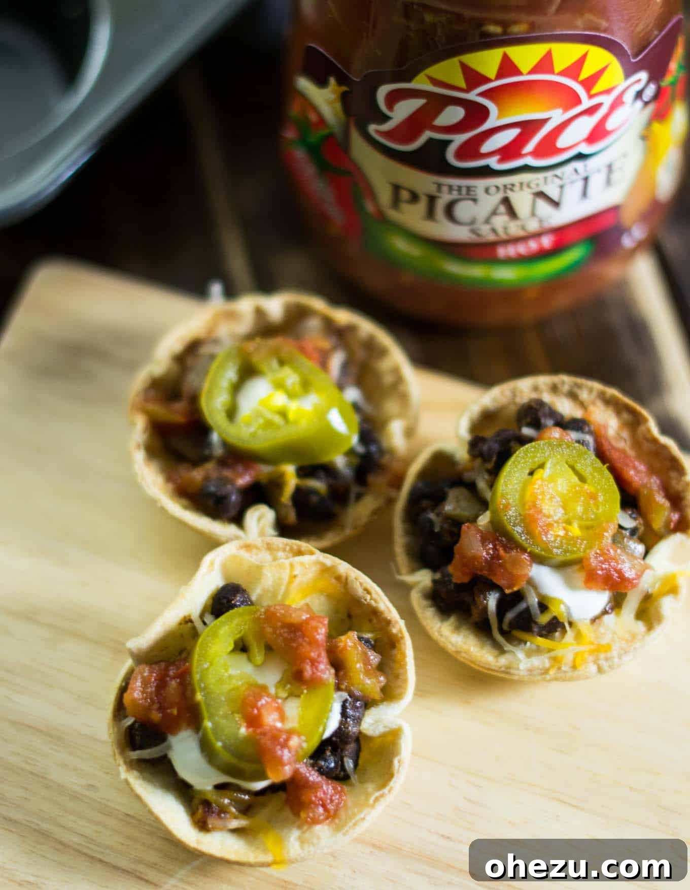 A tray of colorful Vegetarian Taco Cups, filled with a hearty mixture and topped with cheese, salsa, and cilantro.