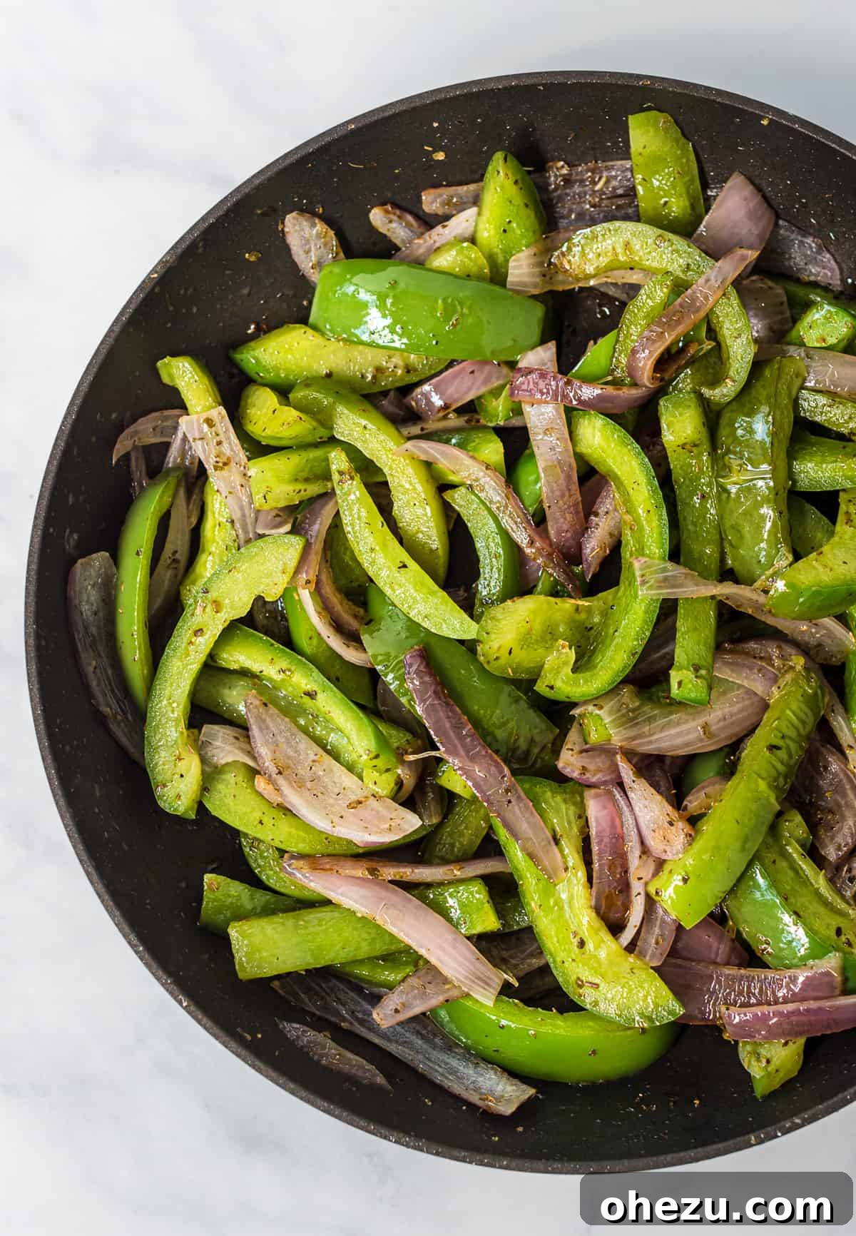 A cast-iron skillet filled with perfectly cooked, colorful fajita vegetables including bell peppers and onions.