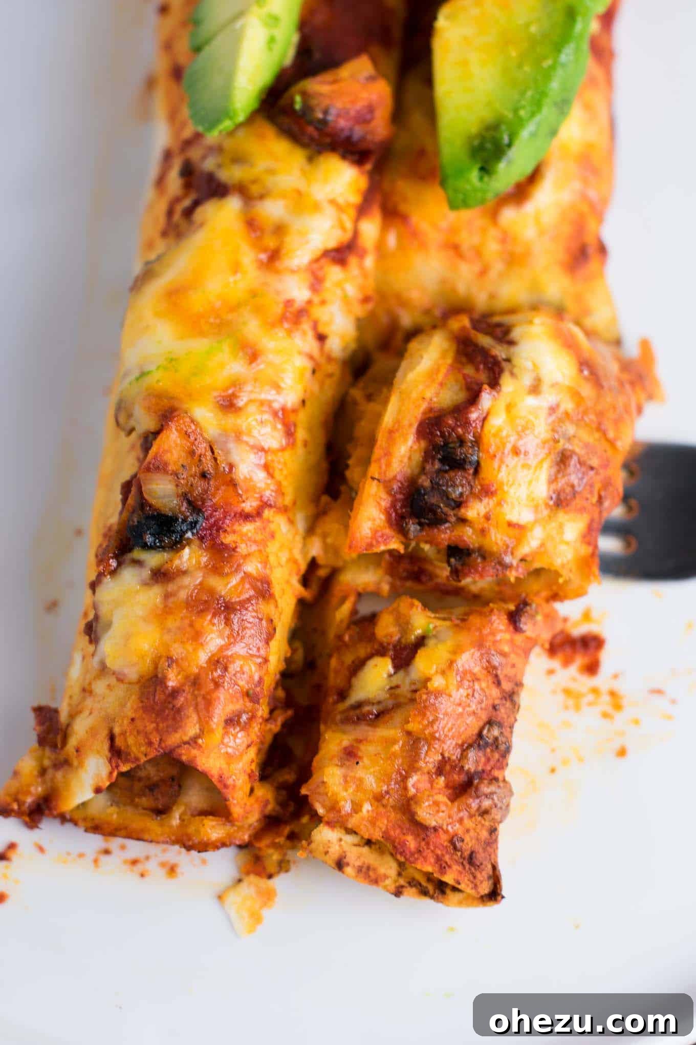 Smoky Sweet Potato Black Bean Enchiladas, baked to a golden brown with melted cheese and fresh green onions, served in a baking dish.