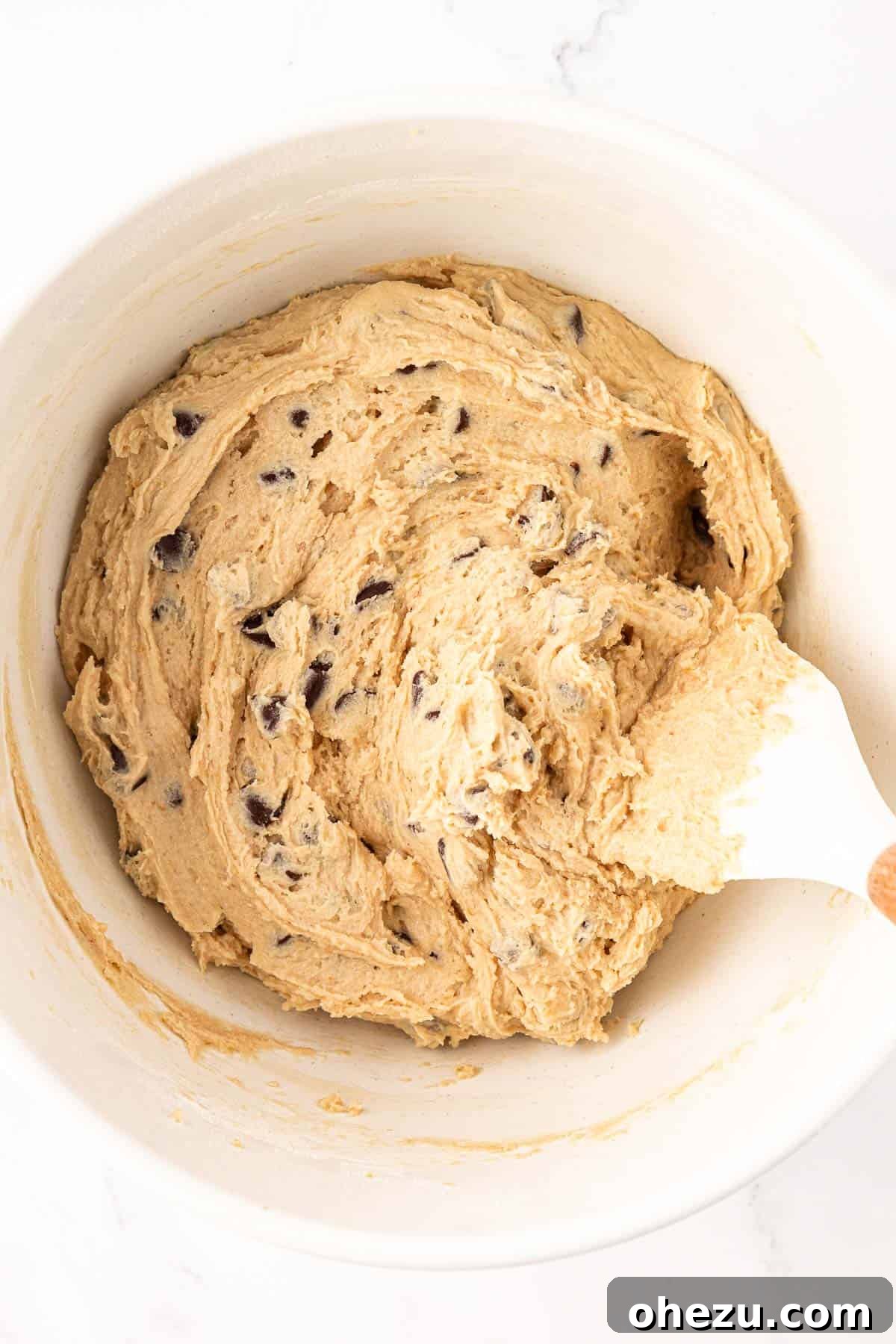 Heavenly Vegan Chocolate Chip Cookies 12 A spatula gently folding dairy-free chocolate chips into the vegan cookie dough, ensuring even distribution.