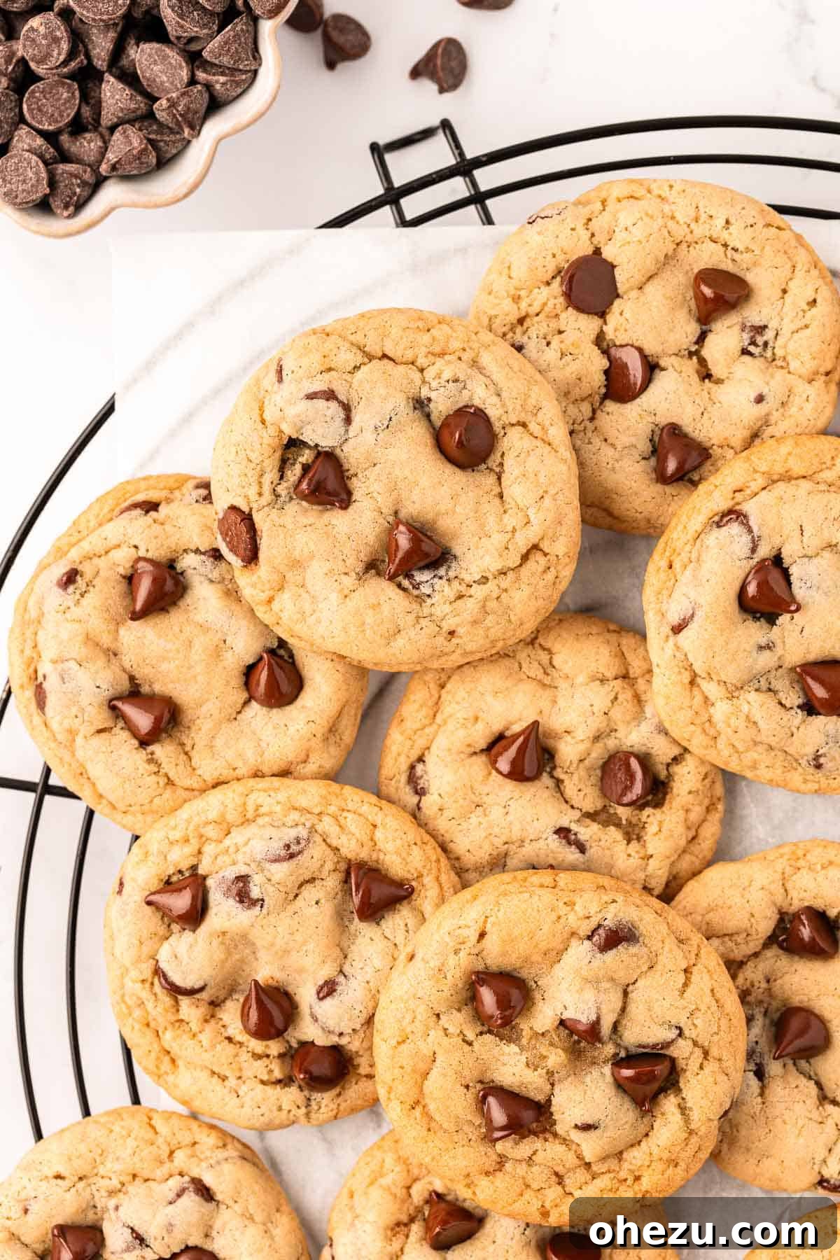 Heavenly Vegan Chocolate Chip Cookies 15 Freshly baked vegan chocolate chip cookies cooling on a wire rack, showcasing their slightly flattened shape and golden brown edges.