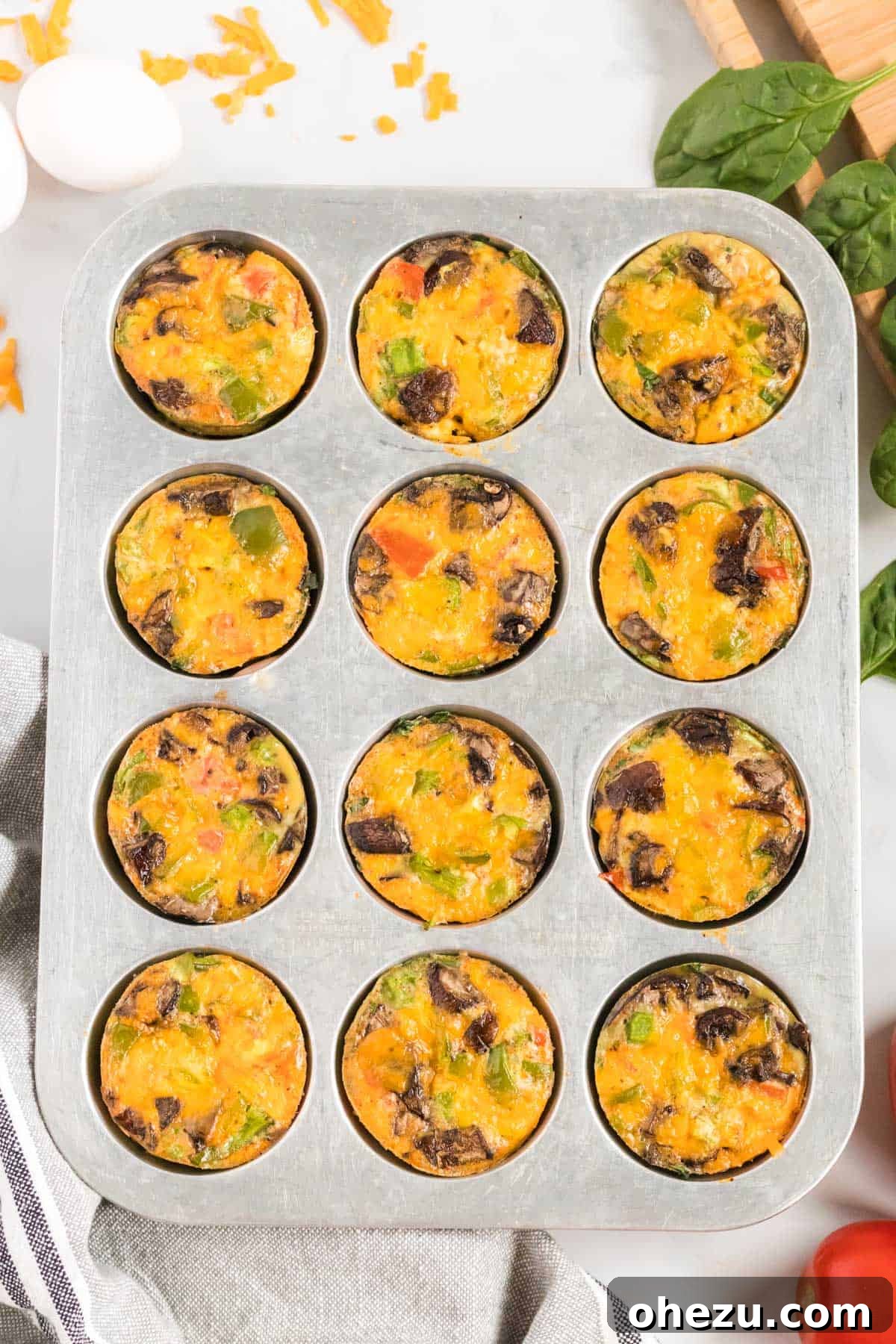 Freshly baked egg muffins cooling in the muffin tin after coming out of the oven, tops golden and edges slightly set.