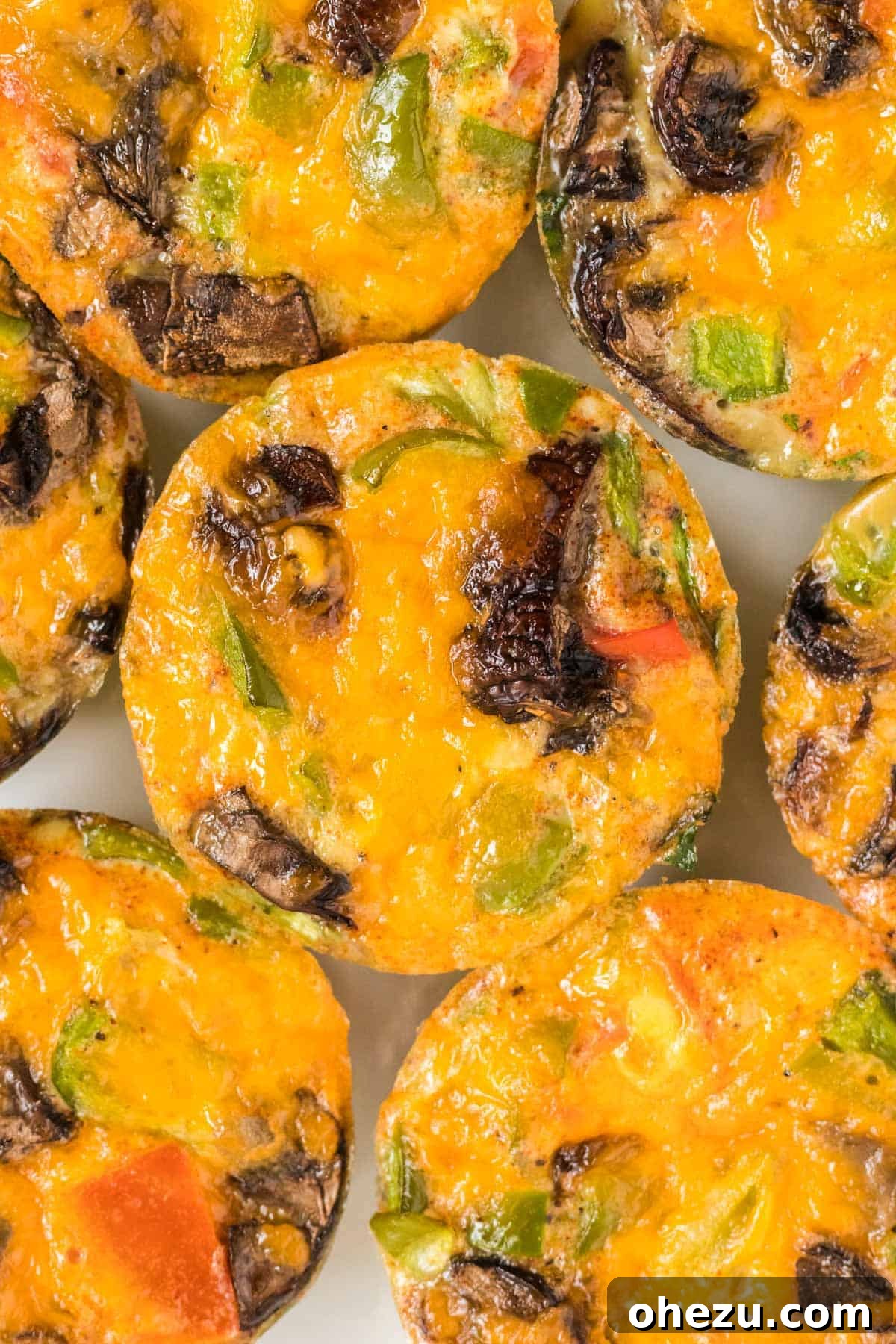 A close-up shot of multiple egg muffins in a visually appealing arrangement, emphasizing their texture and fresh ingredients.