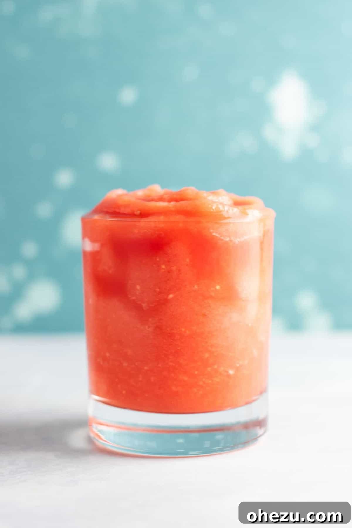 Two glasses of watermelon gin slushies on a patio table, evoking a relaxing summer atmosphere.