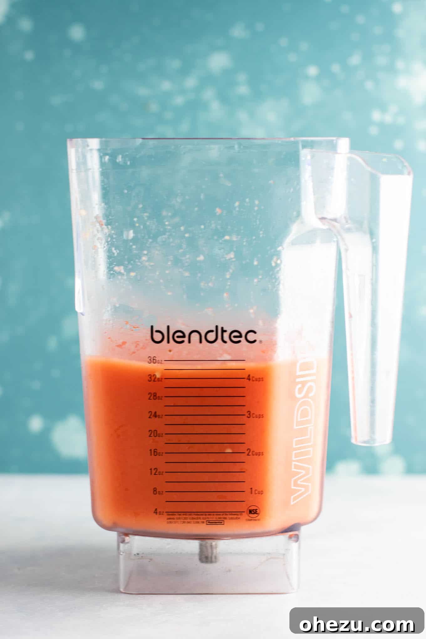 Close-up of a blender filled with frozen fruit and gin, ready to be blended into a slushie.