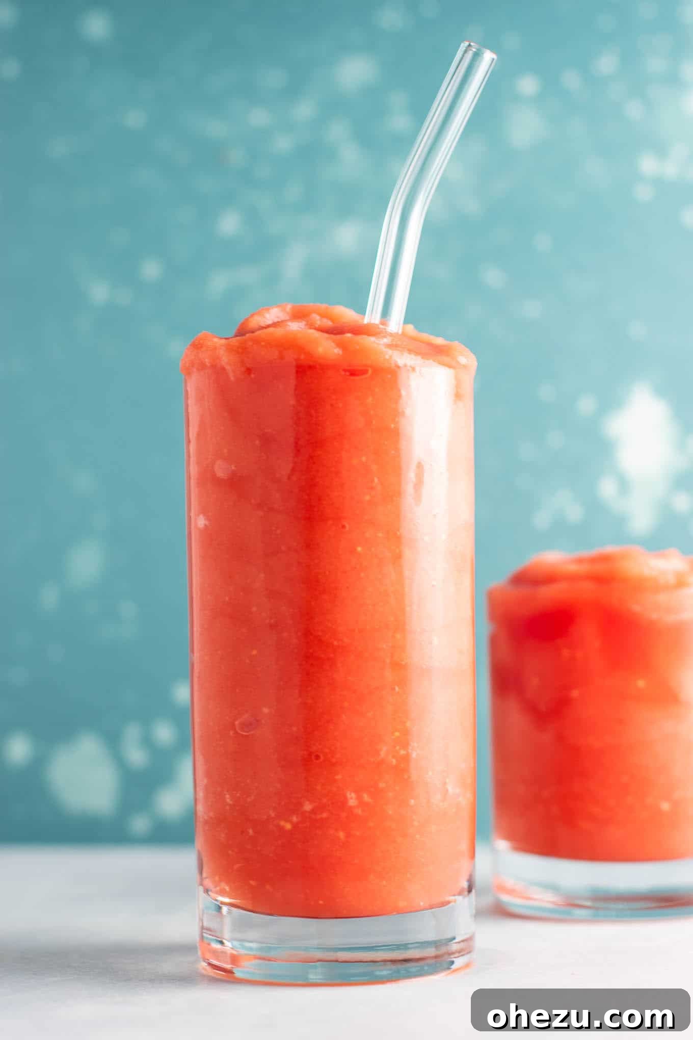 A single glass of watermelon gin slushie with a straw, showing the thick, smooth texture.