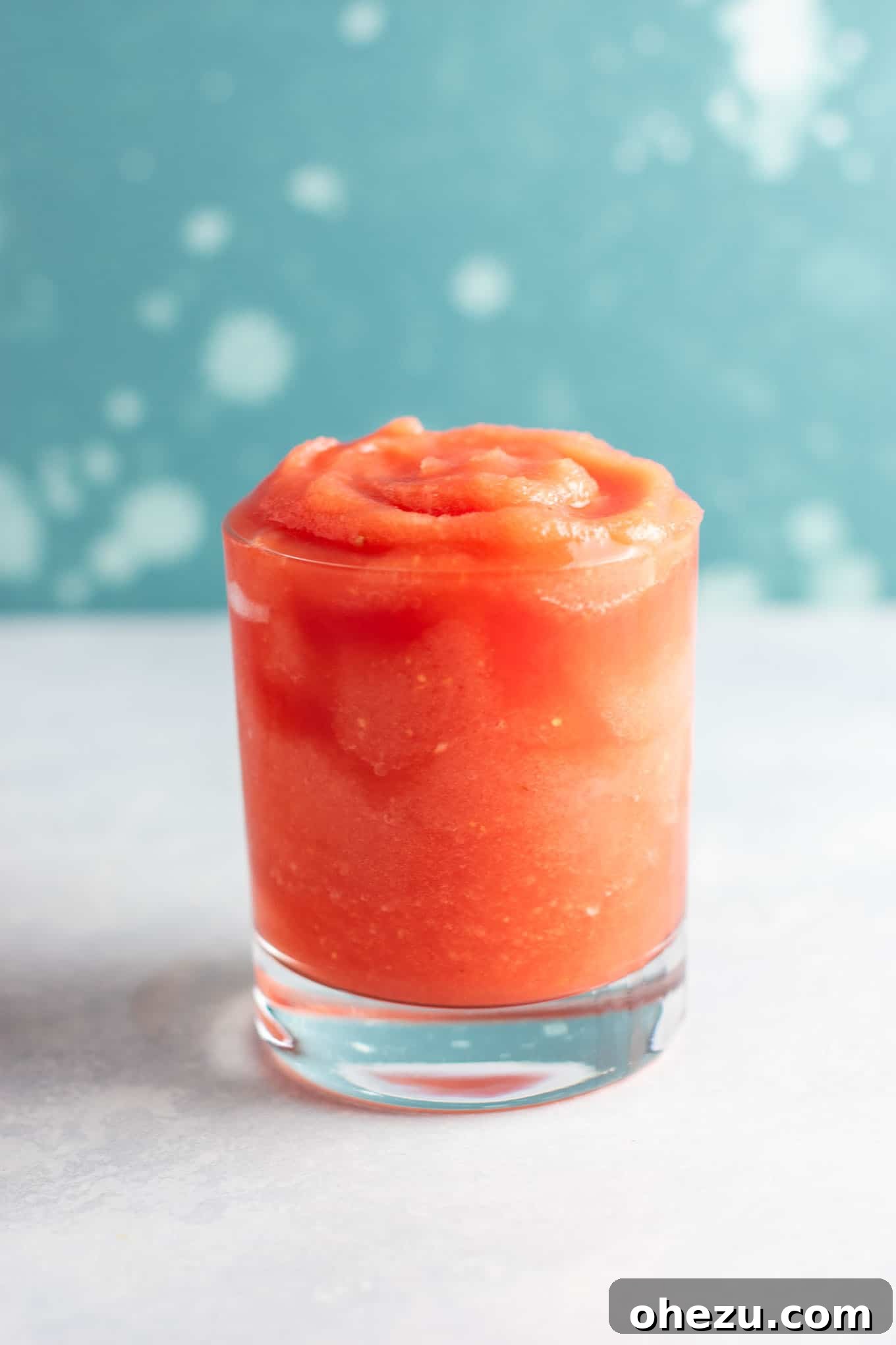 Two hands clinking glasses of watermelon gin slushies in a cheerful outdoor setting.