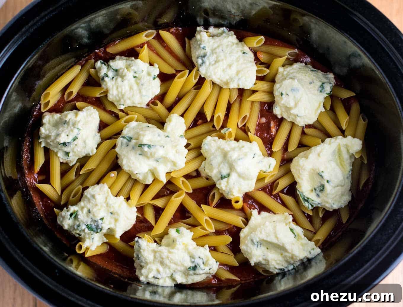 Easy Crock pot Baked Ziti with raw pasta cooking in rich sauce.