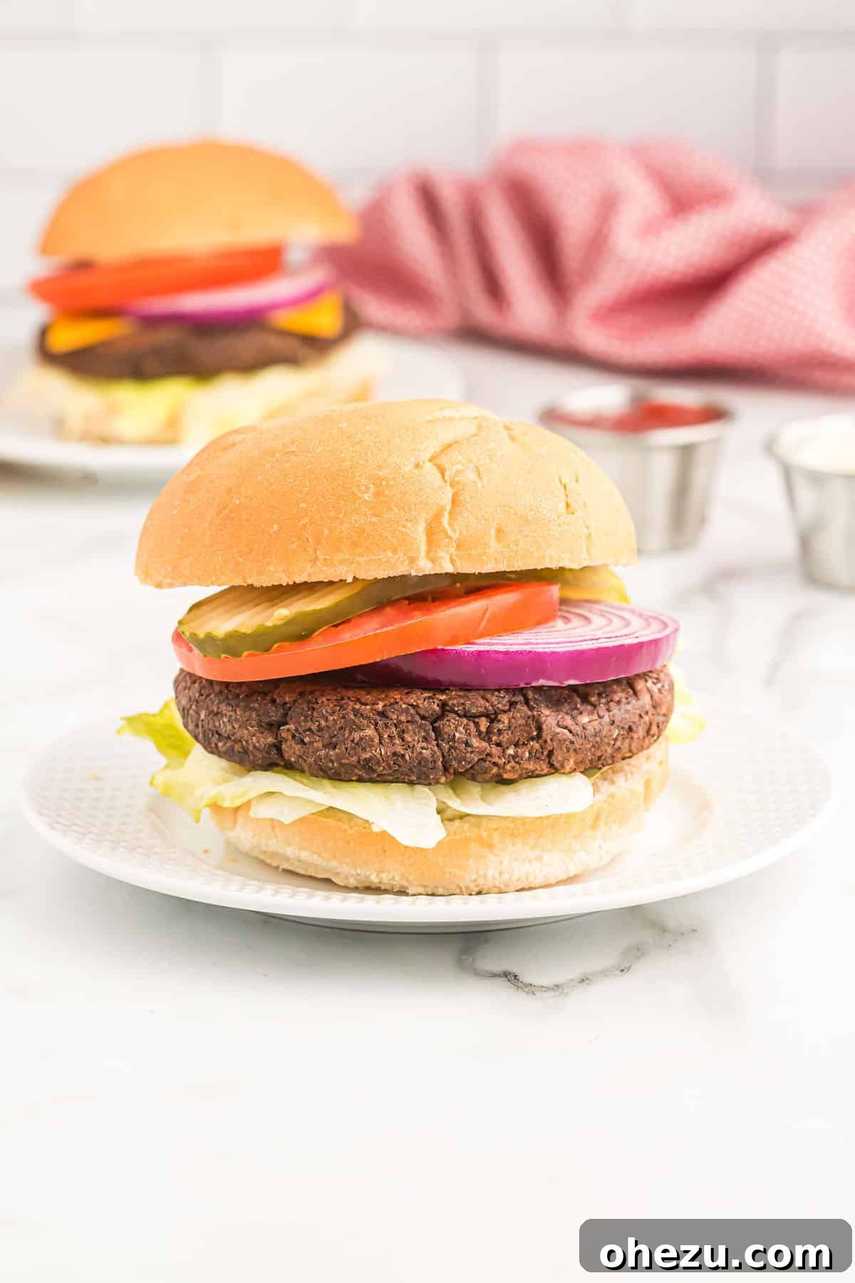 Delicious black bean burger on a bun with pickles, tomato, lettuce, and red onion, ready to be enjoyed.