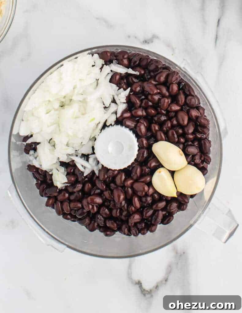 Black beans, garlic, and onion being processed in a food processor to form the burger base.
