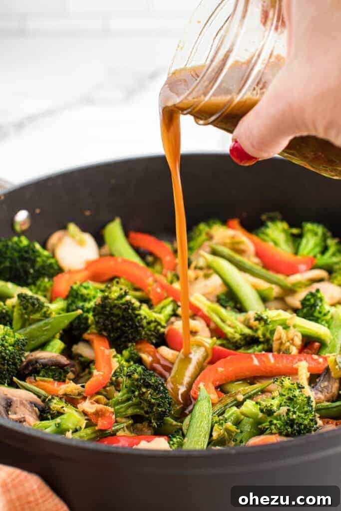 pouring stir fry sauce over vegetables