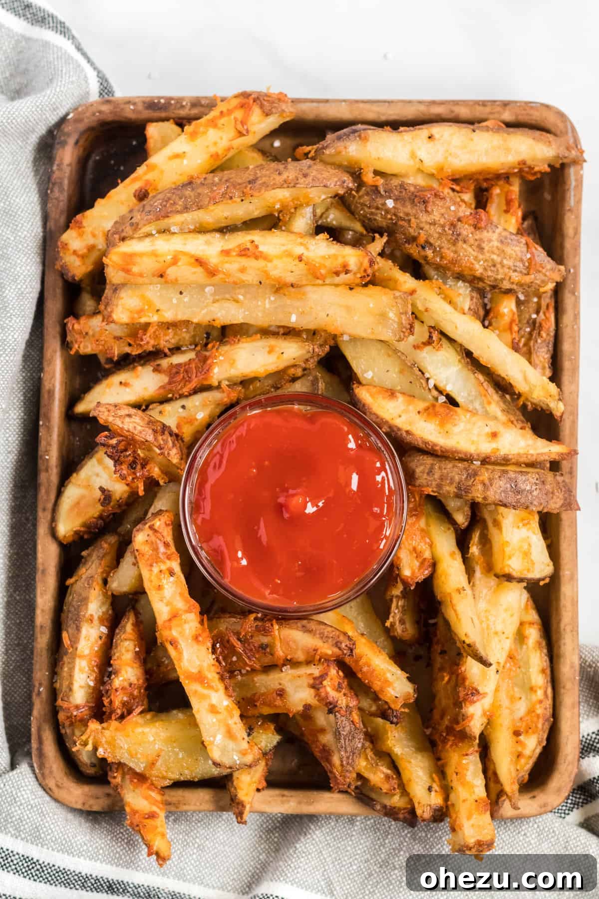 Crispy Parmesan Garlic Potato Wedges served on a brown tray with a small bowl of ketchup in the center