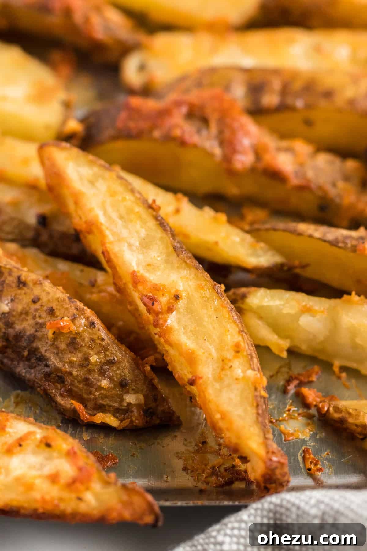 Close-up view of a single crispy potato wedge, showing its golden-brown exterior and cheesy crust