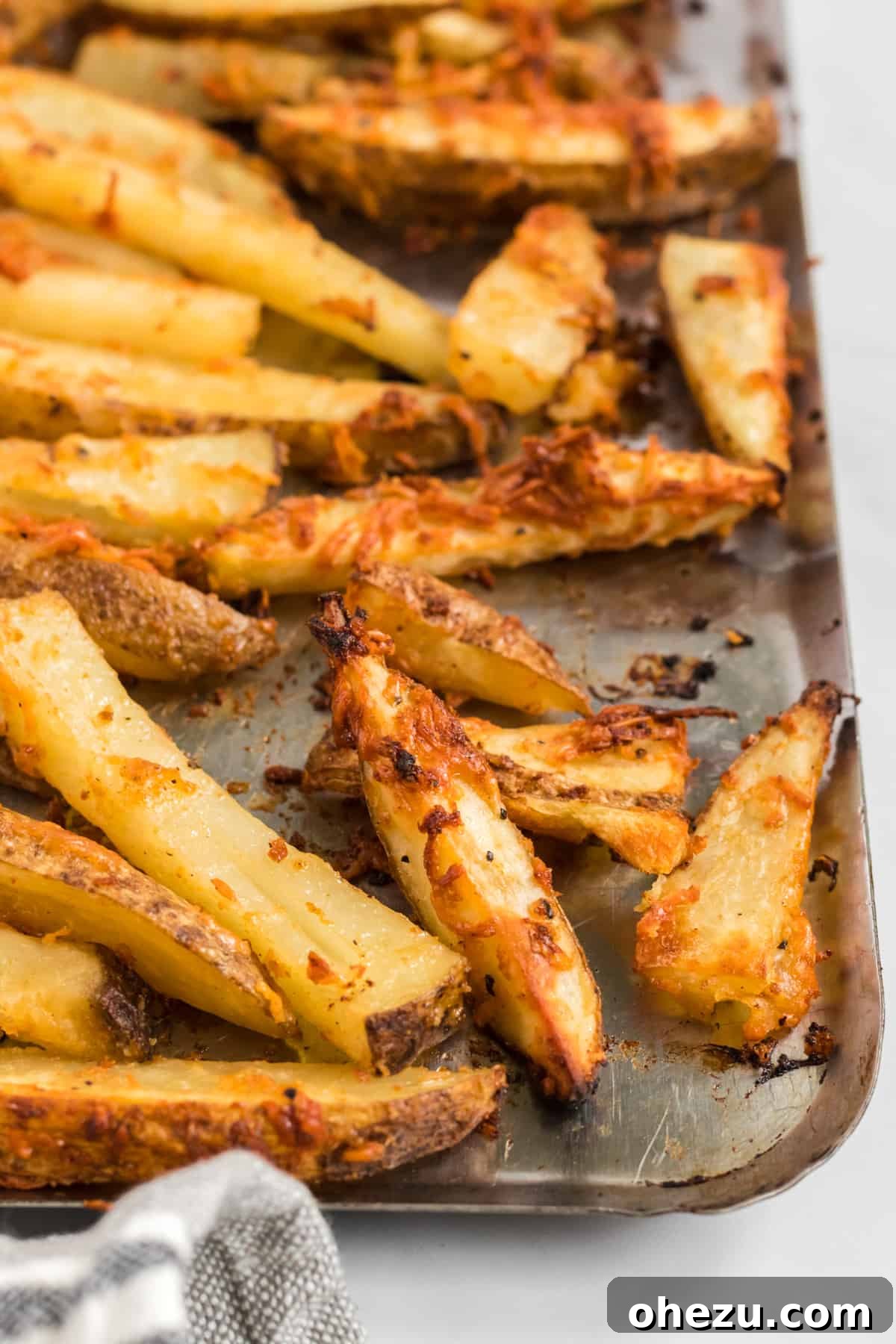 A generous serving of parmesan crusted crispy potato wedges spread across a large baking sheet.