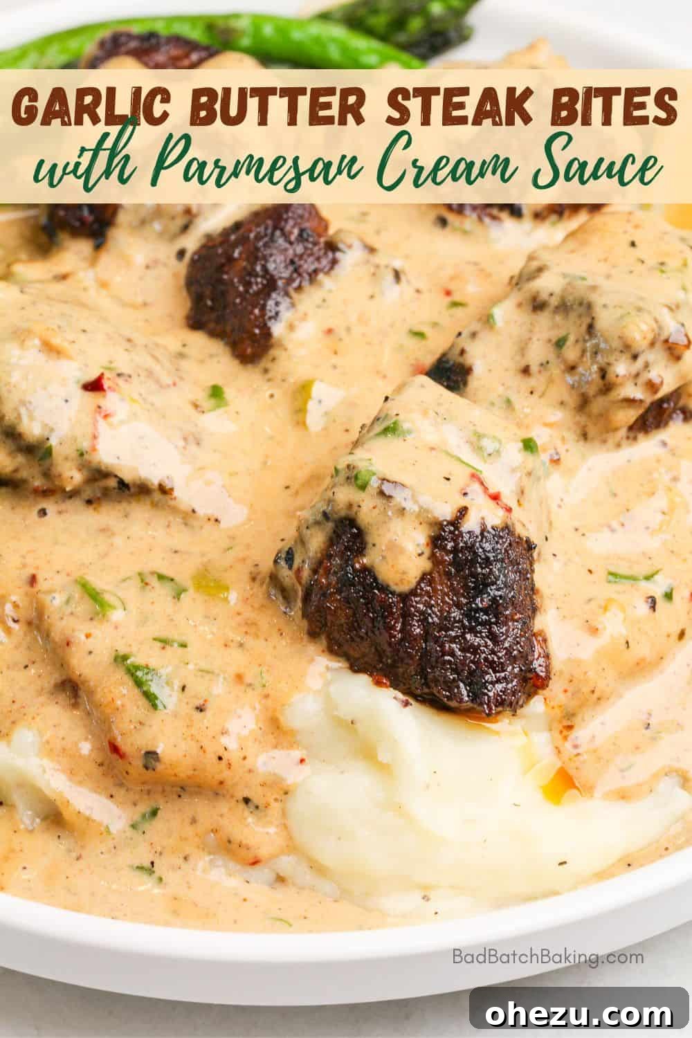 Garlic Butter Steak Bites served with mashed potatoes, garnished with herbs
