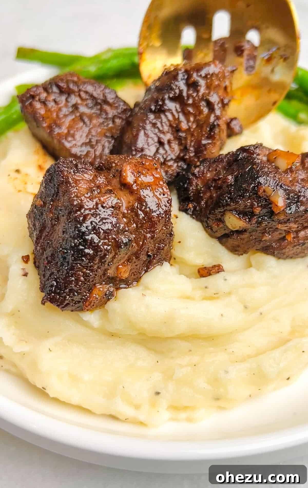 Garlic Butter Steak Bites with creamy sauce and mashed potatoes on a plate
