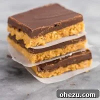 Stack of no-bake chocolate peanut butter bars separated by wax paper.