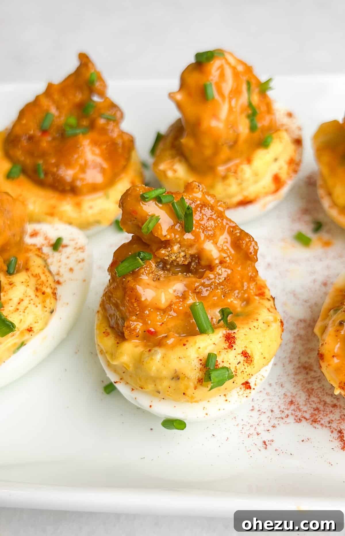 Dynamite Cajun Shrimp Deviled Eggs 7 Beautifully garnished Firecracker Shrimp Deviled Eggs on a clean white plate