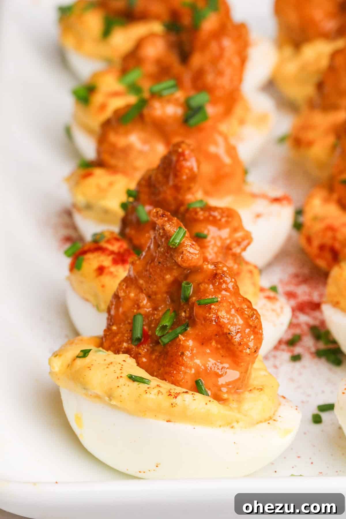 Dynamite Cajun Shrimp Deviled Eggs 3 Close-up view of Firecracker Shrimp Deviled Eggs, showcasing the creamy filling, crispy shrimp, and vibrant sauce