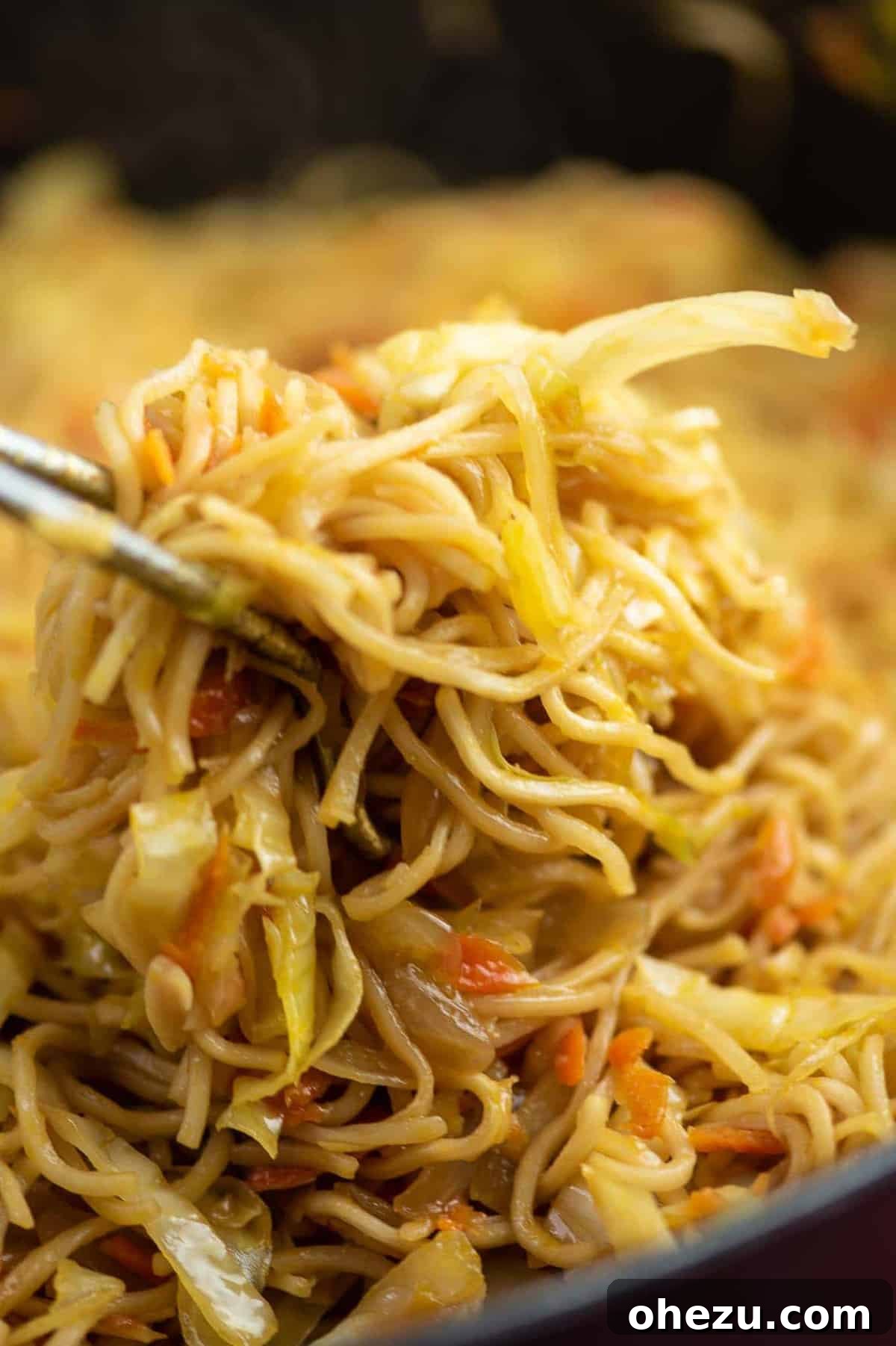 Flavorful Vegan Dinner Creations 13 Delicious Cabbage Stir Fry with ramen noodles, topped with sweet chili sauce, served fresh from a pan with tongs. A perfect vegan takeout alternative. #cabbagestirfry #ramennoodles #veganstirfry #quickdinner