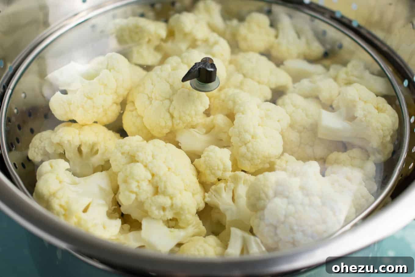 Simple setup for steaming cauliflower: a metal colander nested inside a pot with a lid