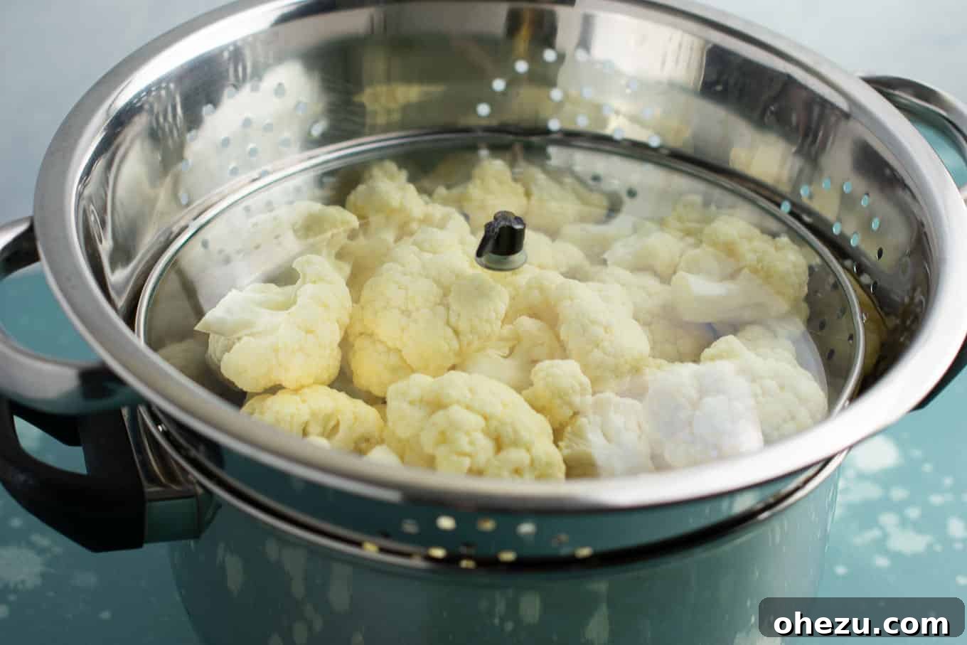Close-up of the pot and colander steaming setup with steam rising, illustrating the method