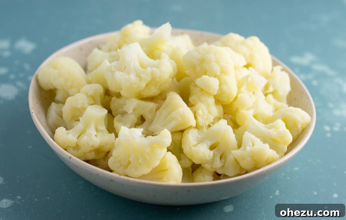 Perfectly steamed, tender cauliflower florets in a white bowl, ready to be seasoned