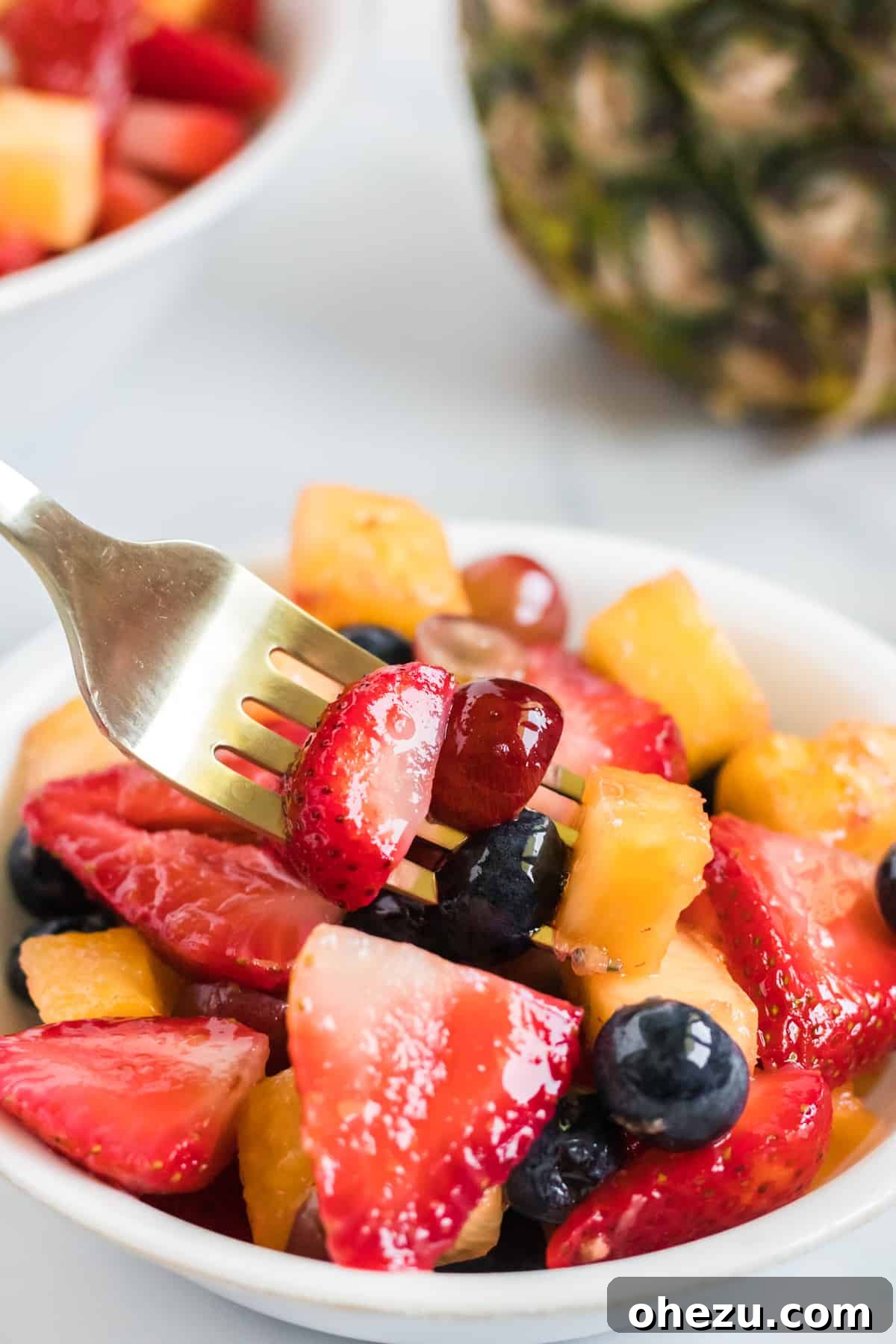 A fork lifting a bite of colorful fruit salad, showcasing the juicy pieces of fruit and a hint of the dressing, ready to be enjoyed.