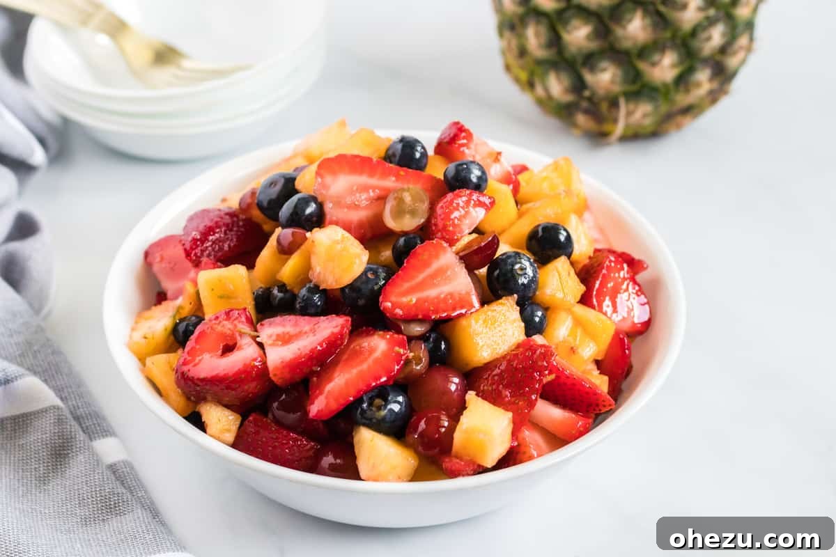 A small white bowl filled with the colorful honey-lime fruit salad, beautifully presented and ready to be served, set against a bright, airy background.