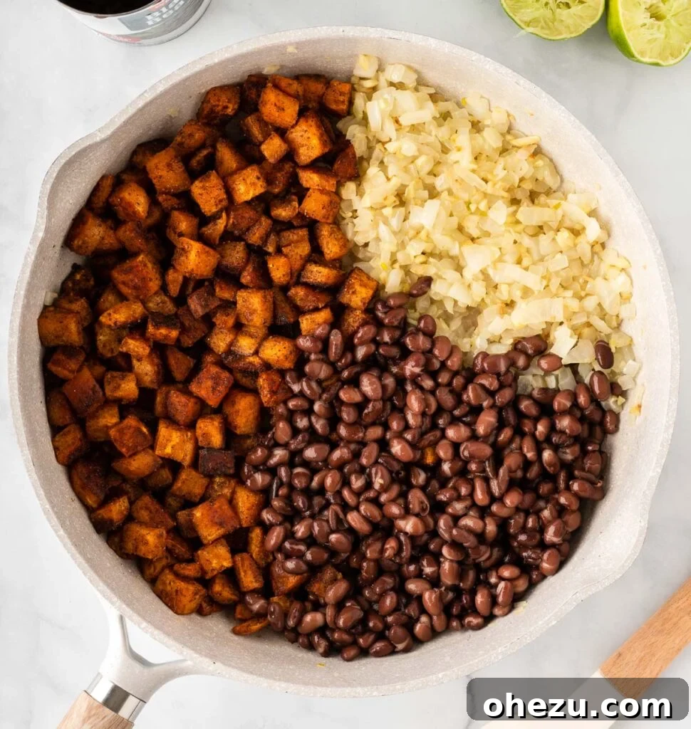 Combining roasted sweet potatoes, black beans, sautéed garlic, and onion in a skillet