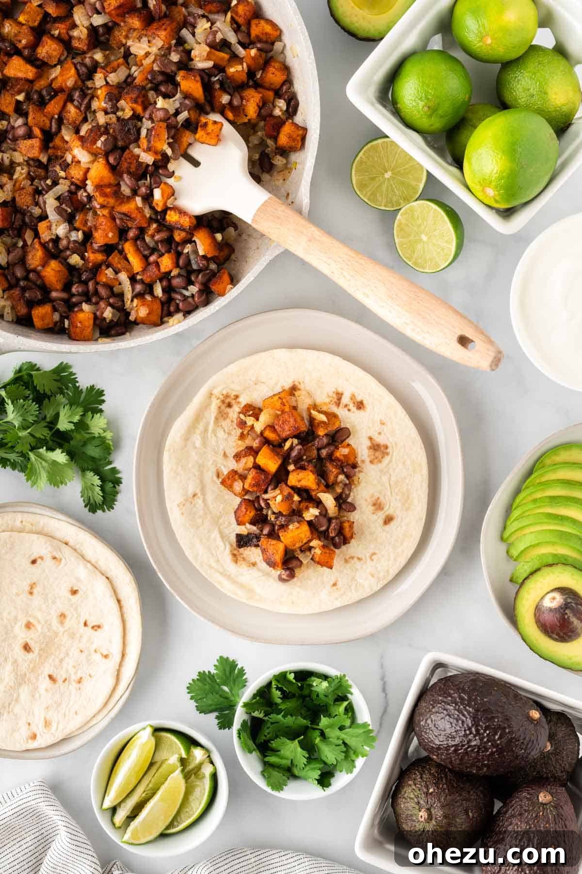 Assembling a sweet potato and black bean taco with fresh toppings