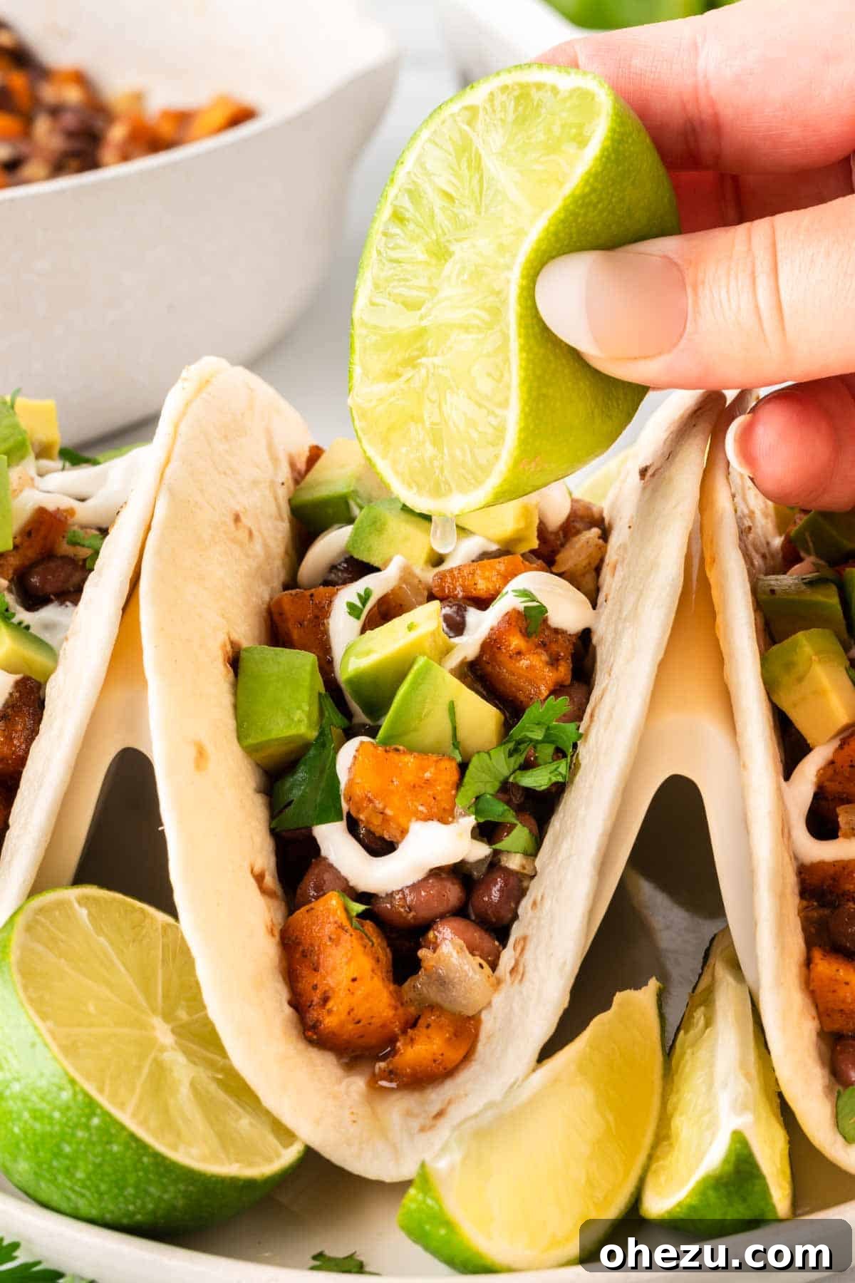 Squeezing fresh lime juice over a sweet potato taco to enhance its flavor