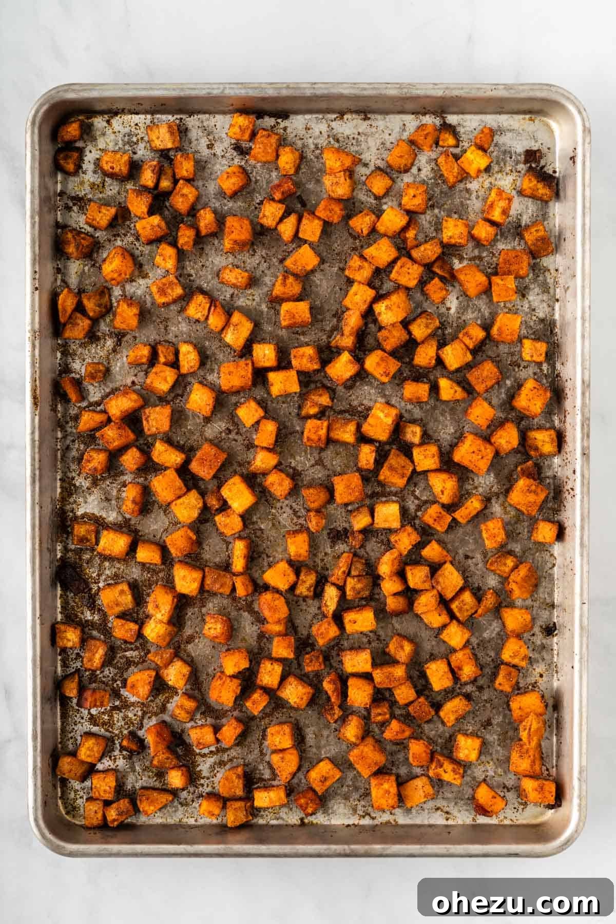 Perfectly roasted sweet potatoes with golden-brown, crispy edges on a baking sheet