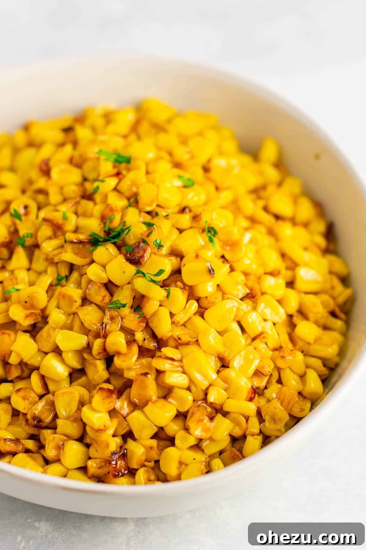 Sizzling Skillet Corn 2 skillet corn for thanksgiving in a bowl, garnished with fresh herbs