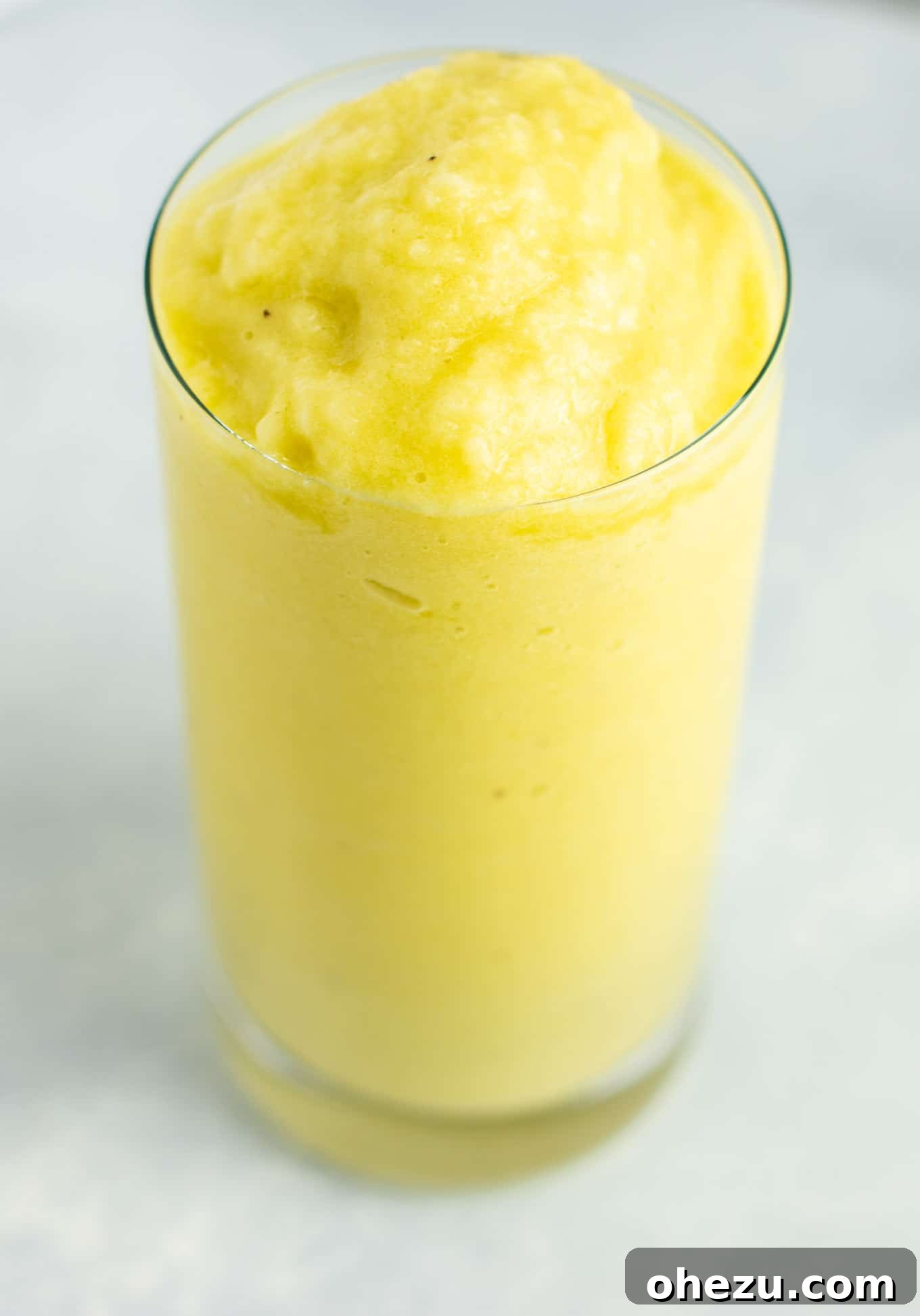 Sunshine Detox Blend 12 A close-up of a glass of pineapple detox smoothie with a pineapple wedge and fresh mint, emphasizing its refreshing qualities.