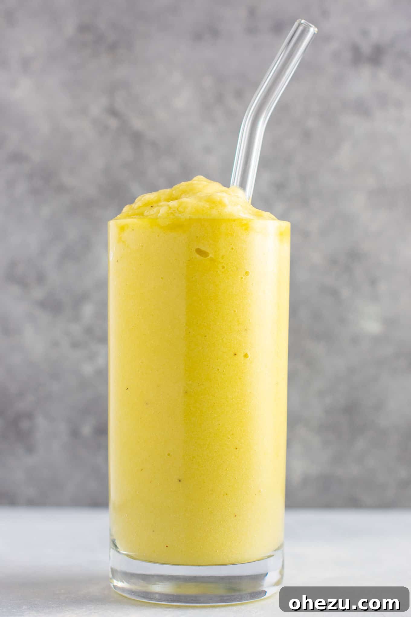 Sunshine Detox Blend 13 Two glasses of pineapple detox smoothie, one in the foreground, one slightly blurred in the background, with fresh fruit scattered around.