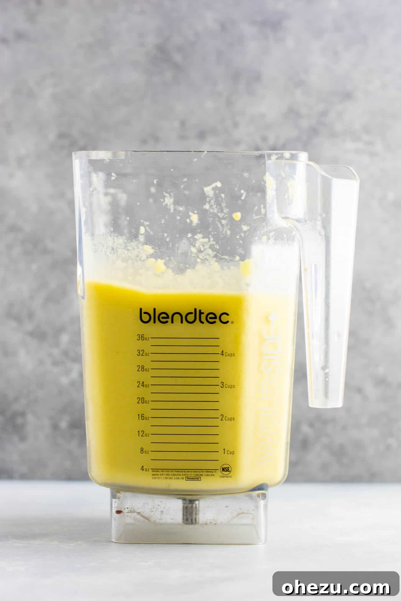 Sunshine Detox Blend 6 A glass of freshly blended pineapple detox smoothie, garnished with a slice of lemon, next to a bowl of fresh pineapple.