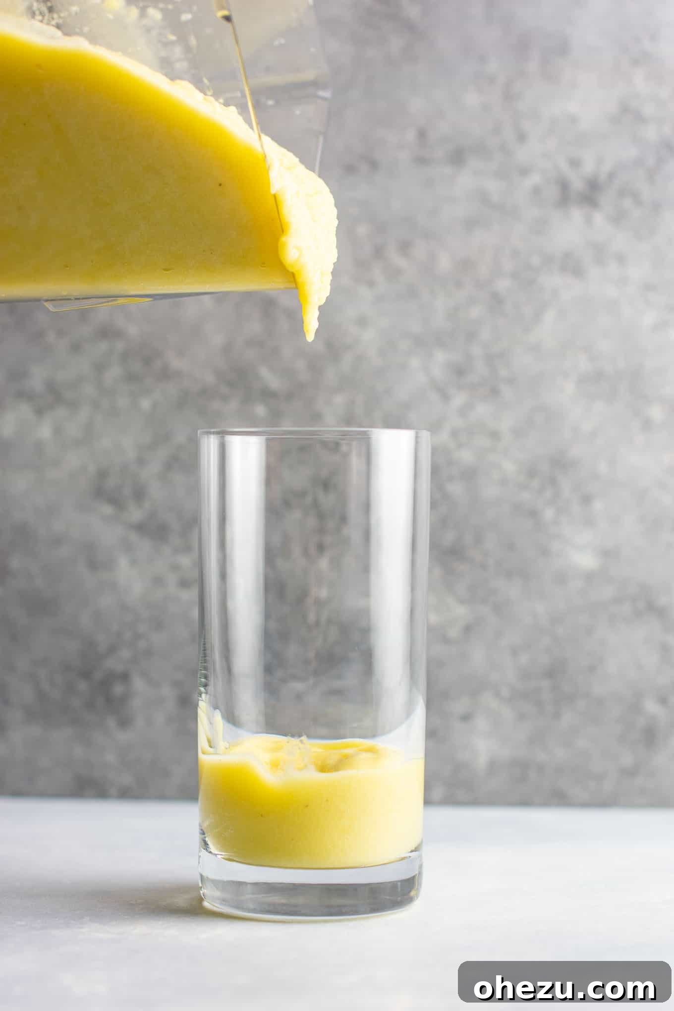 Sunshine Detox Blend 9 A tall glass of pineapple detox smoothie with a metal straw, garnished with a pineapple wedge and mint, looking refreshing and inviting.