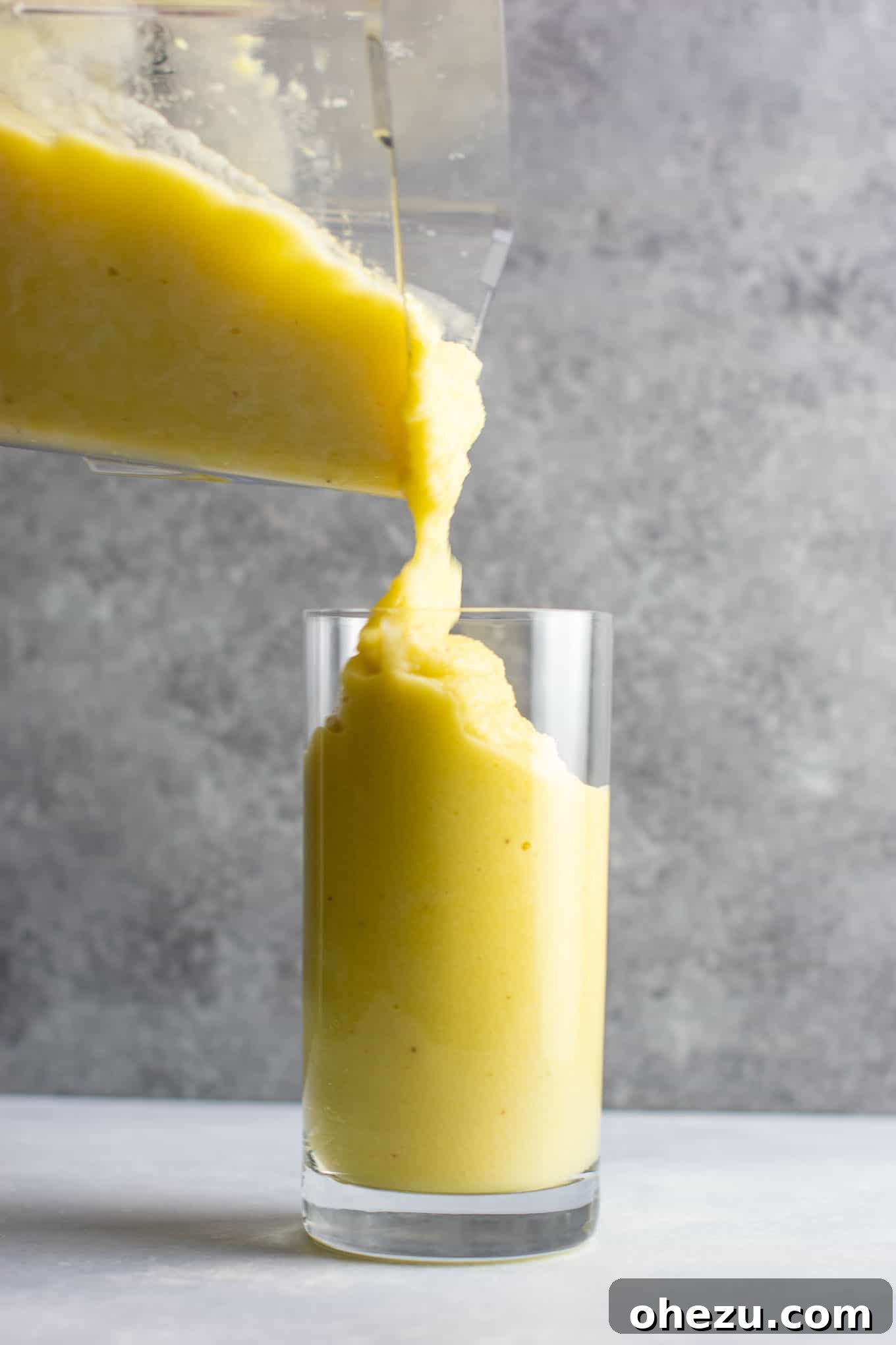 Sunshine Detox Blend 10 Overhead shot of two glasses of pineapple detox smoothie, one garnished with a lemon slice and mint, against a backdrop of fresh ingredients.