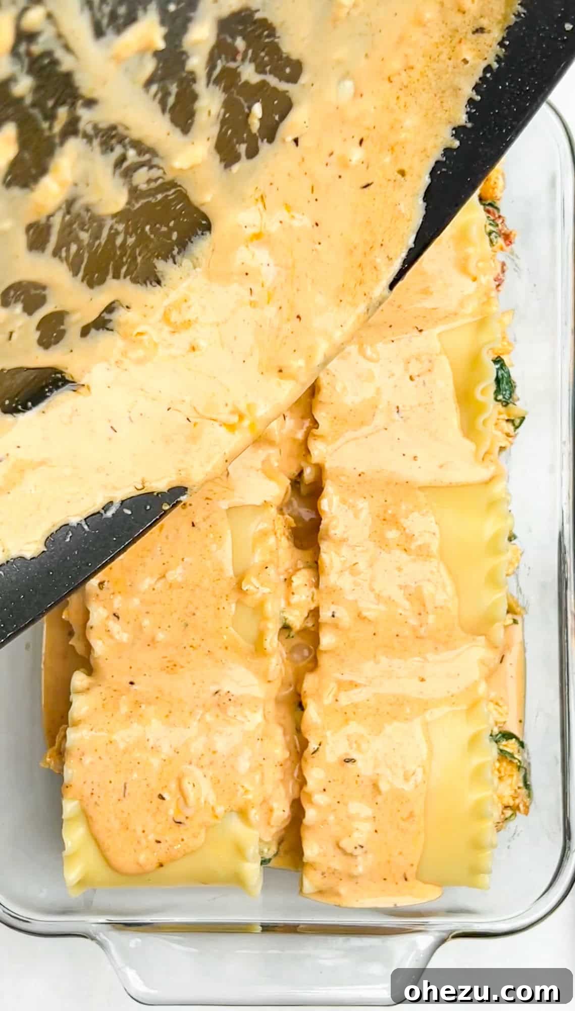 Cajun Chicken Lasagna Roll-ups covered in sauce and cheese, ready for baking